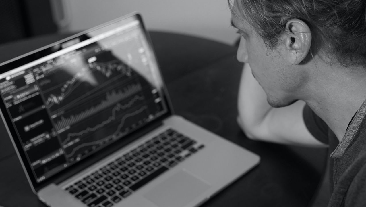 frustrated trader looking at crypto charts on his laptop